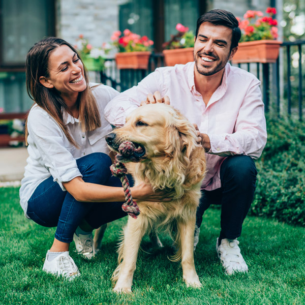 happy couple playing outside with their dog